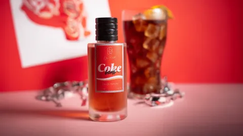 ¿Usarías un perfume con olor a Coca-Cola? La tendencia nostálgica que conquista el mundo beauty Fragancia de Ori Ruso de Coca Cola sobre un fondo rojo y un vaso de Cola