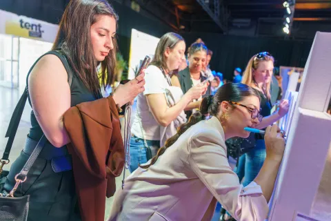 Cómo crear una comunidad en redes sociales: 10 claves para ir más allá de la viralidad Chicas escribiendo en una pared y grabando con el celular.