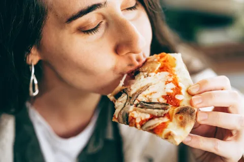 Una mujer comiendo pizza