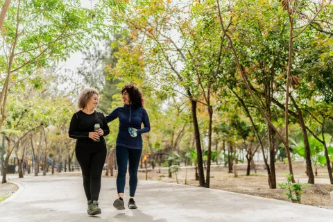 Caminar 20 minutos por día y acostarte media hora antes: por qué estos hábitos pueden cambiar tu vida dos mujeres caminando en el parque
