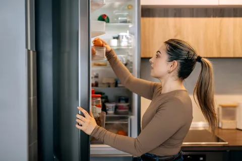 Cómo conservar frutas y verduras por más tiempo y evitar tirar comida una mujer revisa alimentos de la heladera