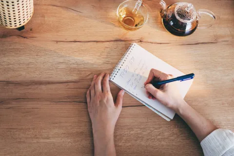 Por qué tener mala letra no es un defecto: lo que revela la grafología sobre la creatividad y el ritmo mental Mano escribiendo en una libreta