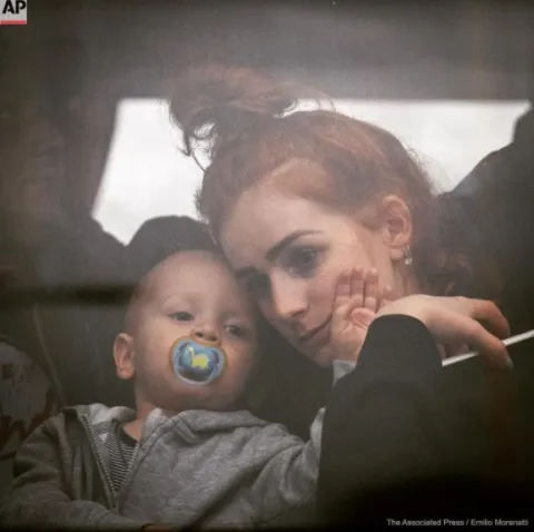 La guerra entre Rusia y Ucrania: historias de mujeres en fotos Una mujer sostiene a su bebé dentro de un autobús cuando salen de Kiev, Ucrania, el jueves 24 de febrero de 2022