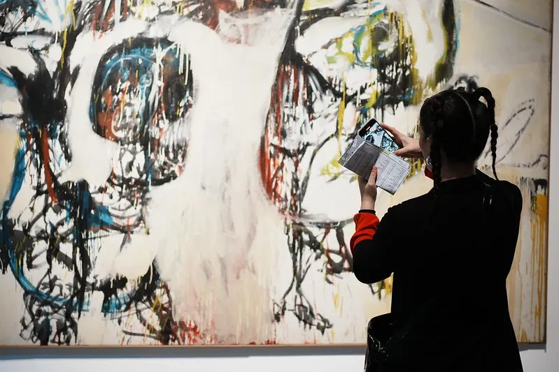 Una mujer sacándole una foto a una obra de arte en ArteBA.
