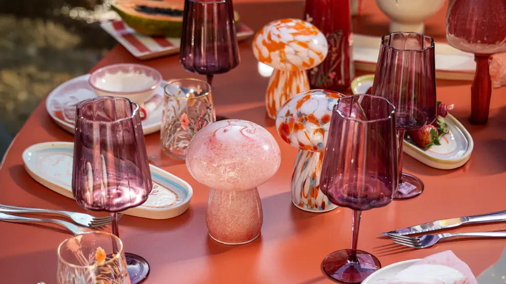 Foto de una mesa terracota con vajilla de color roja y blanca de cerámica y en el medio unas mini lamparas con forma de hongo que combinan con todo