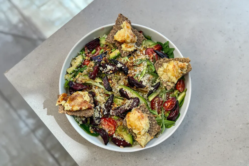 Vista cenital de un plato de ensalada fresca con verdes y legumbres sobre una mesa de marmol